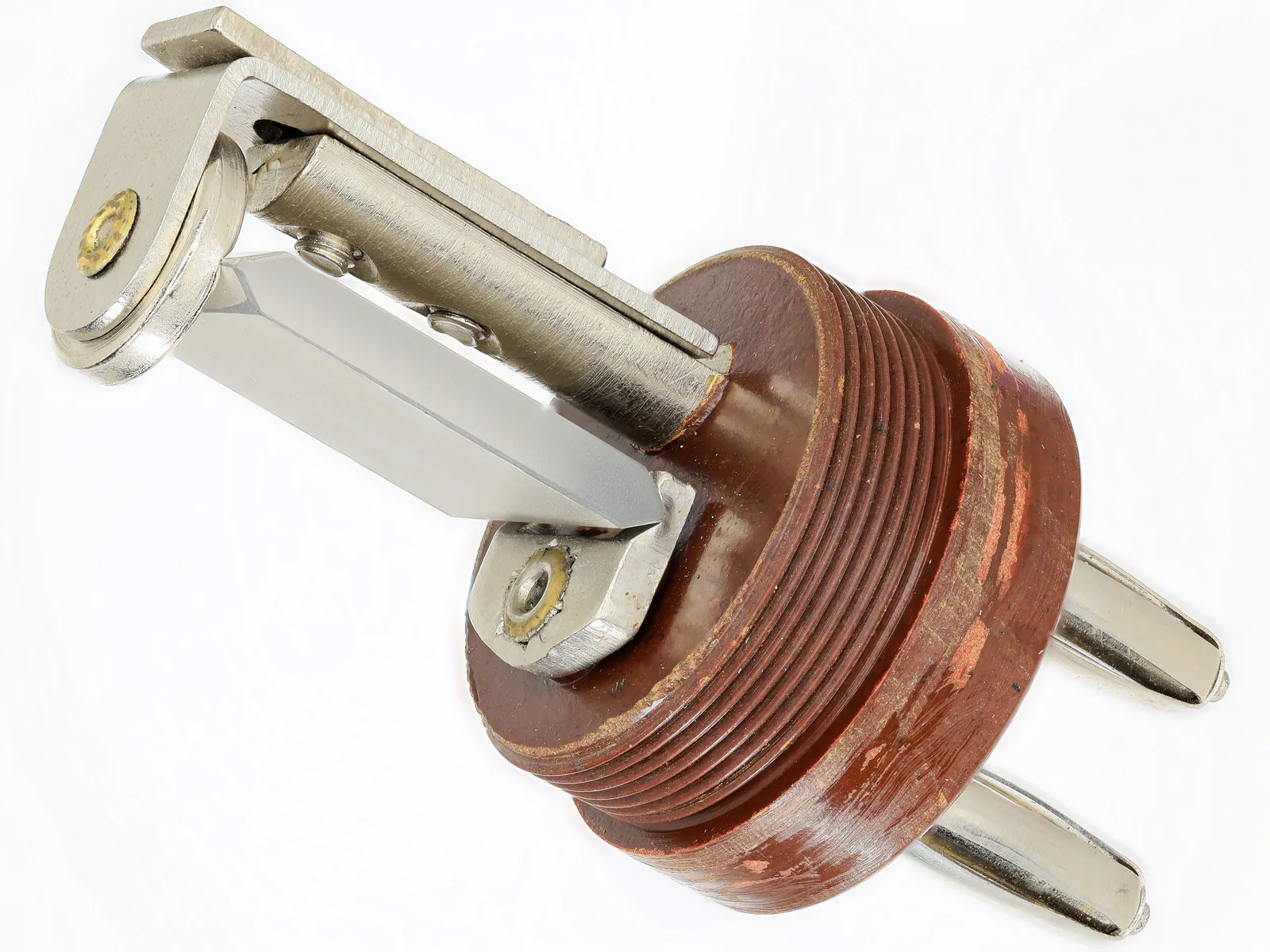 Ein geöffneter alter Schwingquarz: ein flaches, glänzendes Quarzplättchen zwischen Metallhaltern auf einem braunen Sockel mit zwei Steckkontakten.