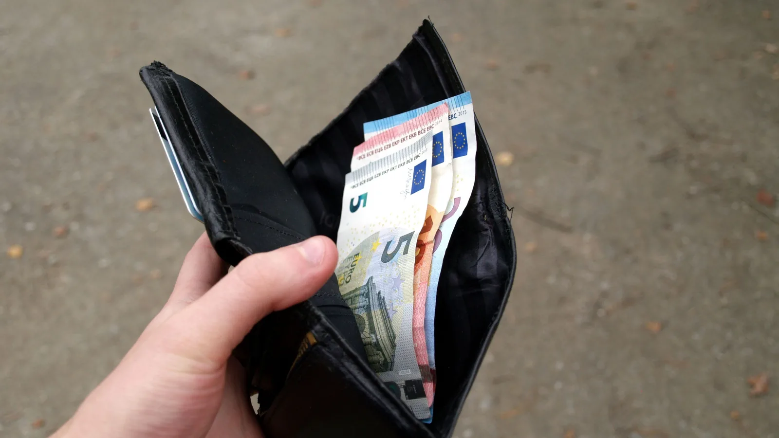 Eine geöffnete schwarze Geldbörse enthält mehrere Eurobanknoten in kleinen Stückelungen.