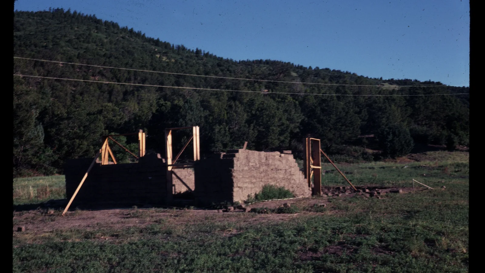 Ein traditionelles Haus mit massiven Adobe-Lehmwänden steht in trockener Landschaft.
