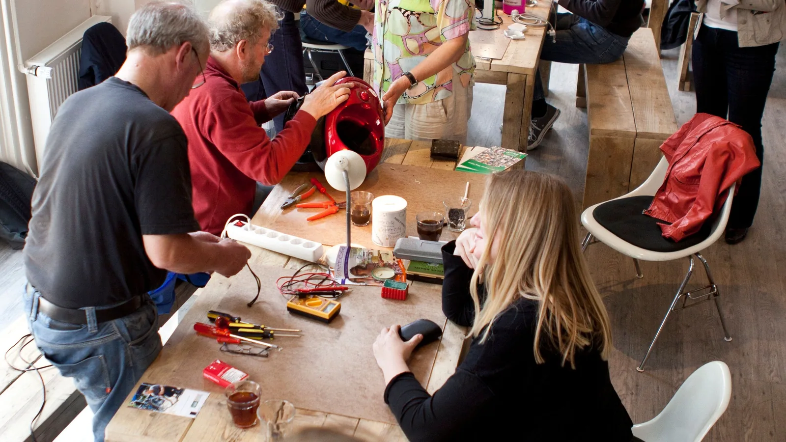 Menschen reparieren gemeinsam in einem Repair Café Alltagsgegenstände und technische Geräte.