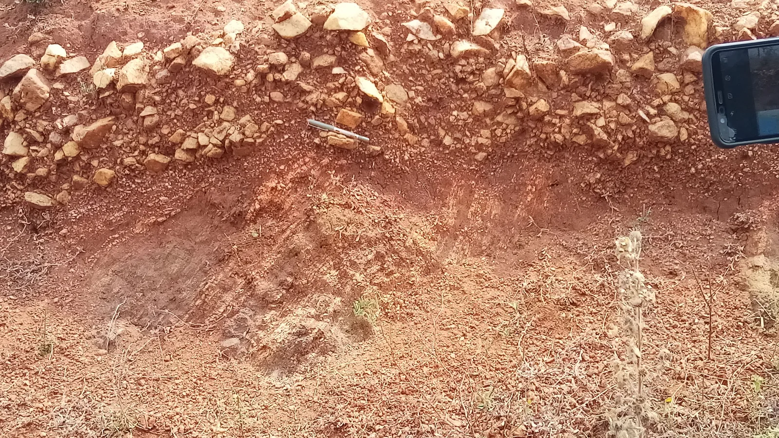 Ein freigelegter Bodenquerschnitt zeigt unterschiedliche Erdschichten mit Steinen, Oberboden und tieferen Bodenzonen.