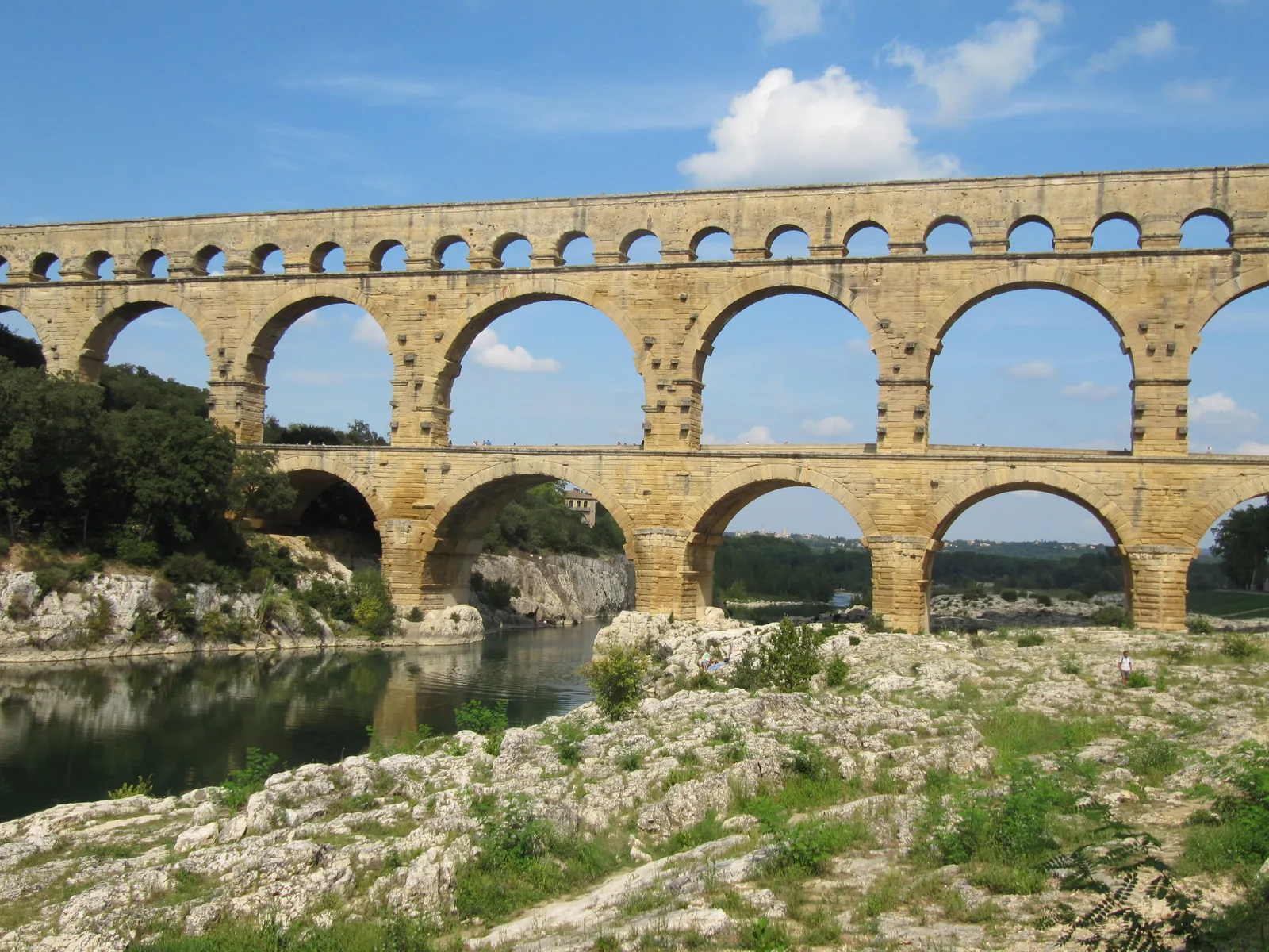 Der Pont du Gard in Südfrankreich: drei Stockwerke aus Steinbögen über dem Fluss Gard, unten große, oben kleine Bögen.