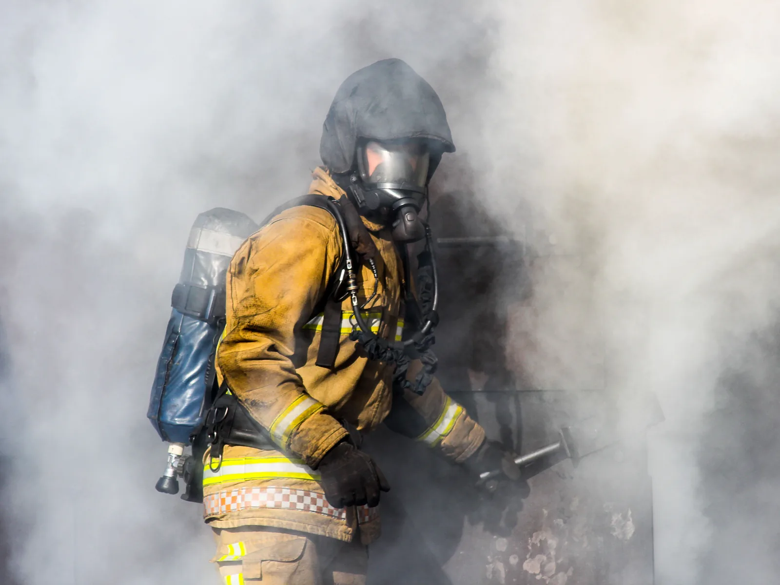 Ein Feuerwehrangehöriger mit Atemschutzgerät bewegt sich während einer Übung durch dichten weißen Rauch.