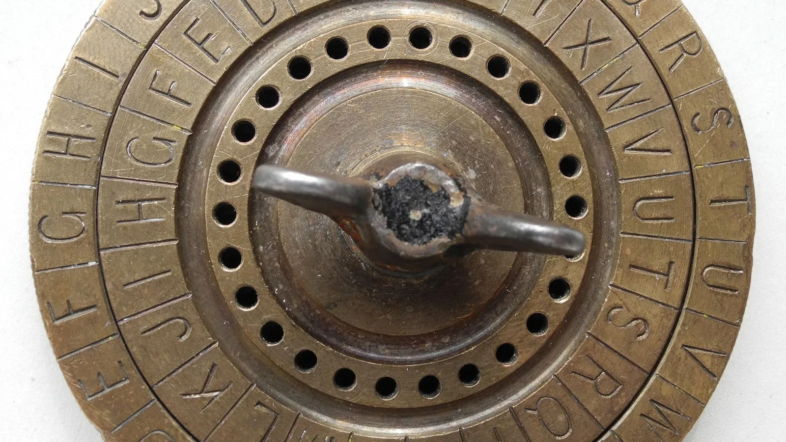 Eine Chiffrierscheibe aus Messing: zwei gegeneinander drehbare Ringe mit je einem Alphabet, in der Mitte ein Flügelgriff zum Verstellen.