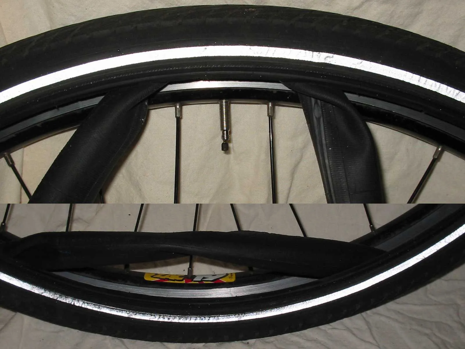 Ein Fahrradschlauch wird zwischen Felge und gelöstem Reifenmantel vorsichtig herausgezogen.