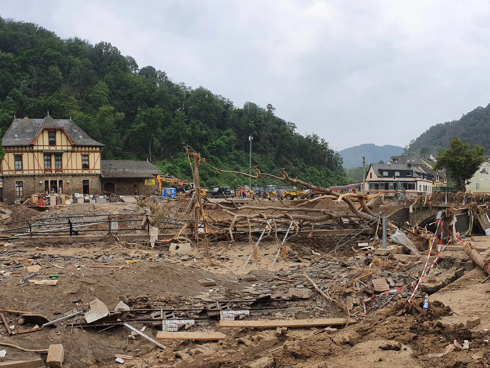Verwüstetes Ufer in Altenahr acht Tage nach der Flut mit Trümmern, umgestürzten Bäumen und beschädigter Infrastruktur.