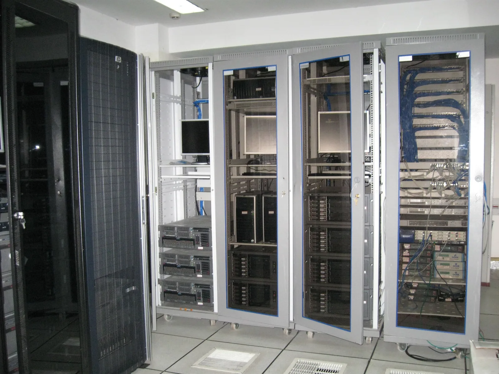 Realer Serverraum mit mehreren Serverschränken, Netzwerkverkabelung und IT-Systemen.