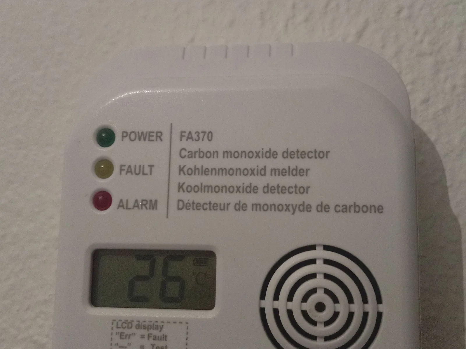Ein weißer Kohlenmonoxidmelder mit Display und Statusanzeigen ist an einer Innenwand montiert.