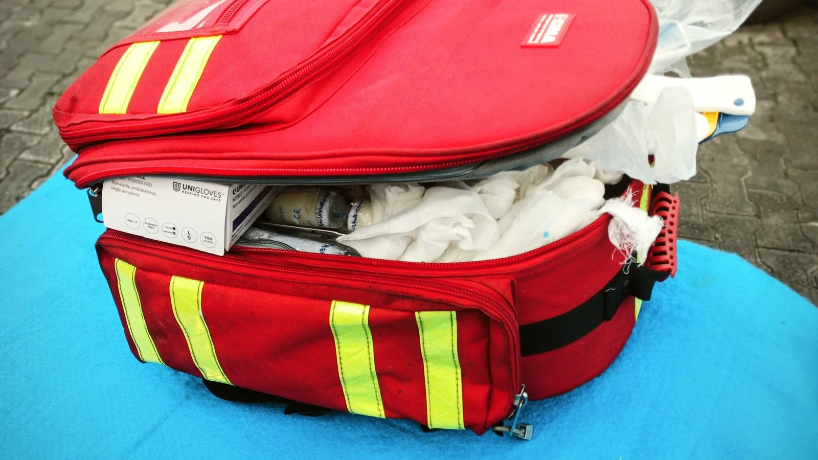 Geöffneter Erste-Hilfe-Kasten mit Verbandmaterial, Schere, Handschuhen und weiteren grundlegenden Hilfsmitteln.