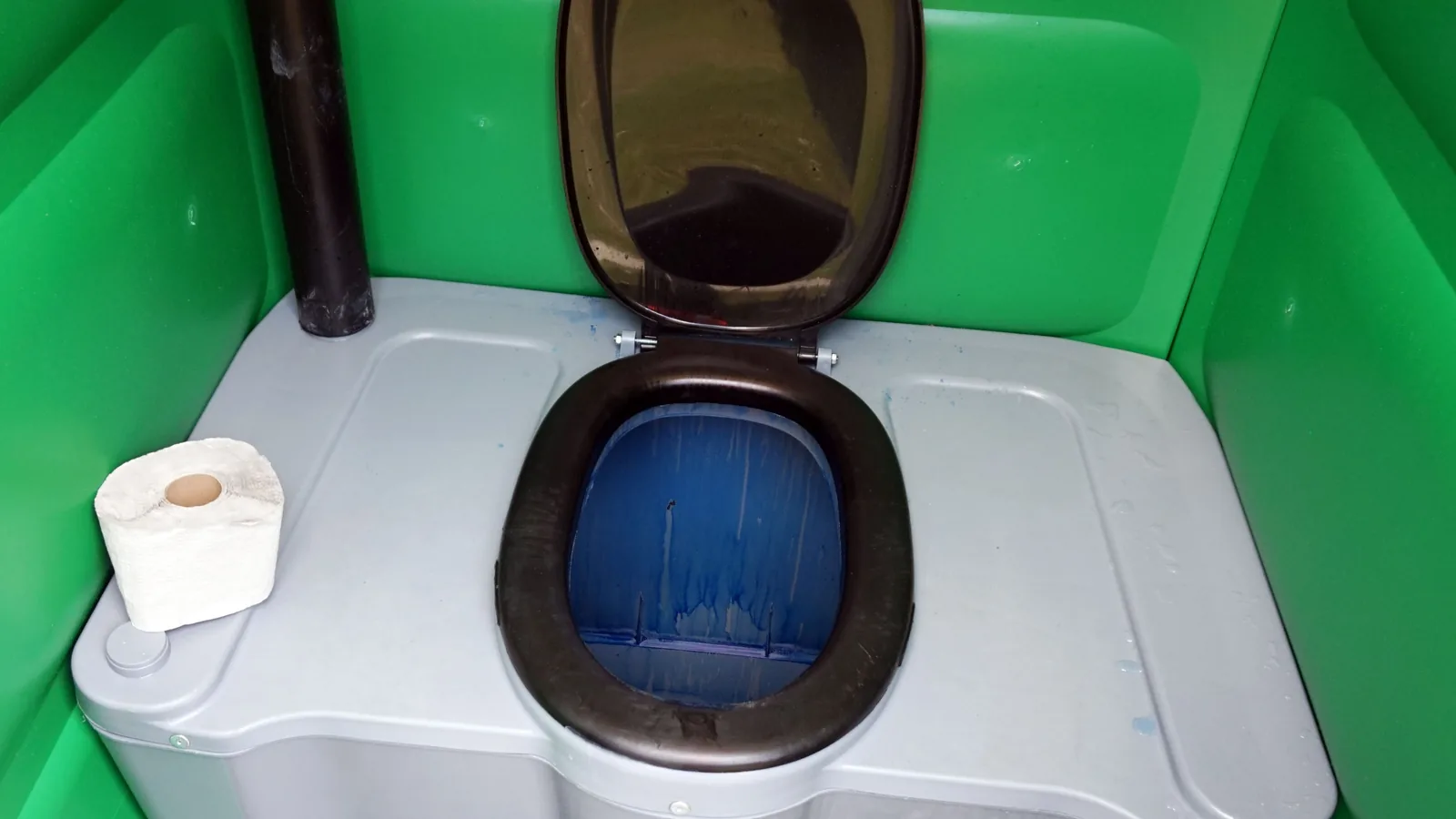 Eine mobile Toilette steht im Freien auf festem Untergrund.