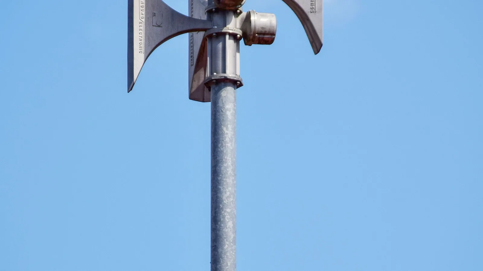Mehrere elektronische Warnsirenen sind auf einem Gebäudedach montiert.