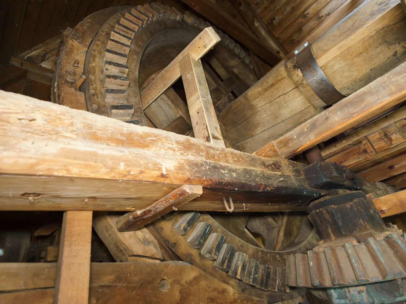 Blick ins Getriebe einer Windmühle: große Holzräder mit eingesetzten Holzzähnen zwischen schweren Balken.